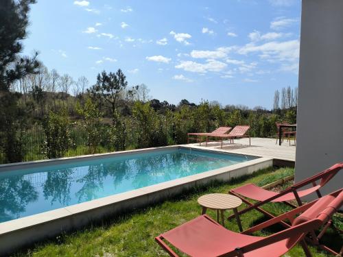 a swimming pool with chairs and a table at Villa Holidays Ocean in Messanges