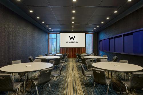 a conference room with tables and chairs and a large screen at W Philadelphia in Philadelphia