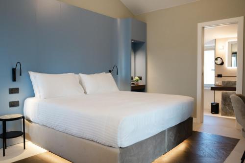 a bedroom with a large white bed and a chair at Emme Palace Hotel & Spa in Orvieto