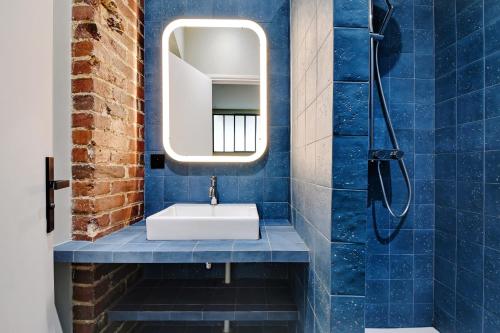 une salle de bain bleue avec un lavabo et un miroir dans l'établissement Pick A Flat's apartment in Monmartre - Rue Etex, à Paris