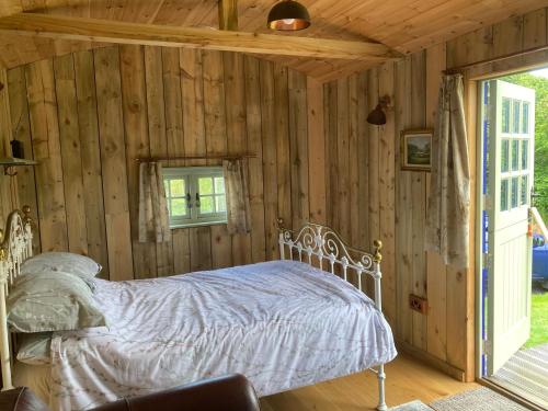 a bedroom with a bed in a wooden wall at Fox lodge Shepherd Hut Sidmouth in Sidmouth