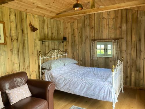 a bedroom with a white bed in a room with wooden walls at Fox lodge Shepherd Hut Sidmouth in Sidmouth
