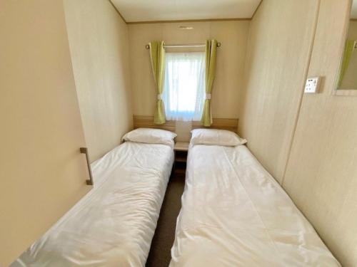 two beds in a small room with a window at Trieste, Waterside in Goodrington