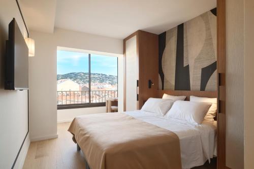 une chambre avec un lit et une grande fenêtre dans l'établissement 6 Croisette Beaches Sea View and Palais des Festivals, à Cannes