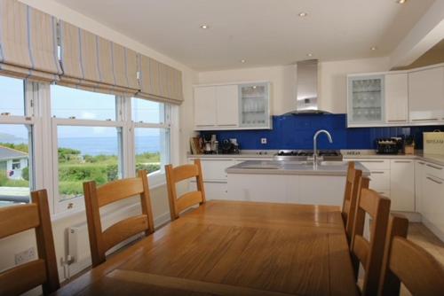 a kitchen with white cabinets and a table and chairs at Cliff House, Cornwall in Padstow