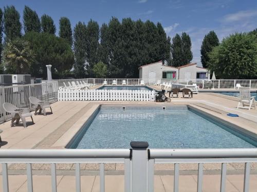 une piscine avec des chaises et une clôture dans l'établissement Le Marais - Village Vacances, à Meschers-sur-Gironde