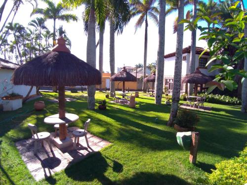 a yard with a table and chairs and palm trees at OYO Pousada do Wagner, Rio das Ostras in Rio das Ostras
