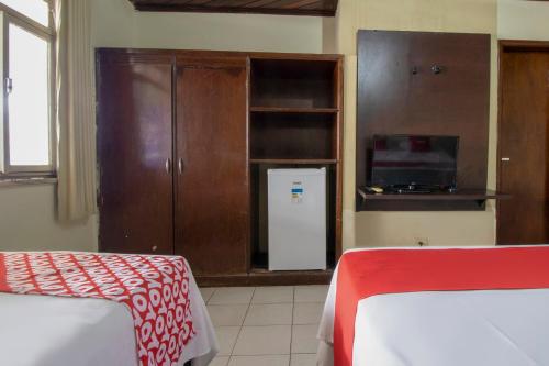 a room with two beds and a cabinet and a microwave at OYO New Anápolis Hotel, Imperatriz in Imperatriz