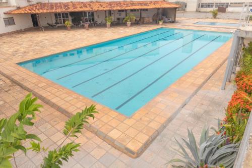 a large swimming pool in a courtyard with a house at OYO New Anápolis Hotel, Imperatriz in Imperatriz