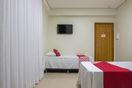 a room with two beds and a tv on the wall at OYO Tropical Confort Hotel, Brasilia in Brasilia