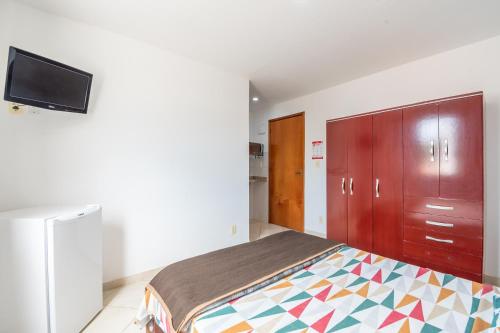 a bedroom with a bed and a tv on a wall at OYO Residencial Muriqui Apart Hotel, Mangaratiba in Vila Muriqui
