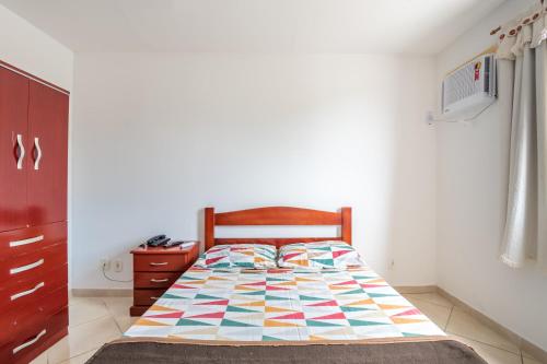 a bedroom with a bed with a colorful quilt on it at OYO Residencial Muriqui Apart Hotel, Mangaratiba in Vila Muriqui