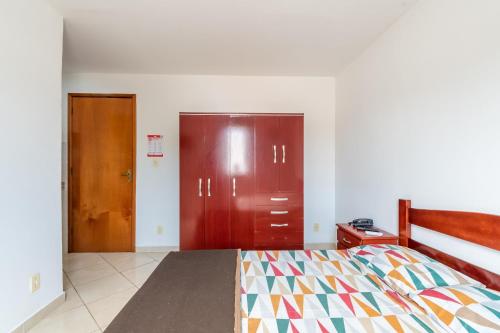 a bedroom with a bed and two wooden doors at OYO Residencial Muriqui Apart Hotel, Mangaratiba in Vila Muriqui