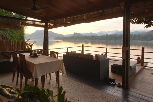 a living room with a table and a view of a lake at Nongkham in Luang Prabang
