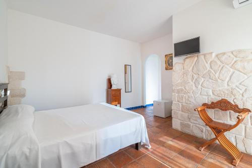 a bedroom with a white bed and a wooden chair at Al Palmento Relais in Siracusa