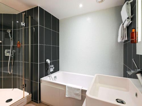 a bathroom with a tub and a shower and a sink at Novotel Suites Paris Issy Les Moulineaux in Issy-les-Moulineaux