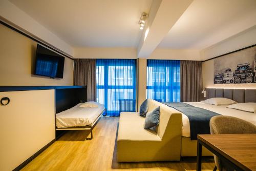 a hotel room with a bed and a couch and windows at Ostend Hotel in Ostend