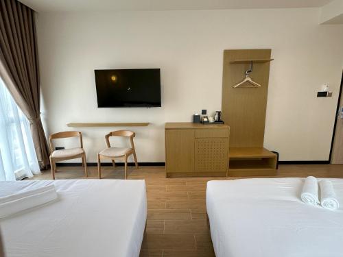 a hotel room with two beds and a flat screen tv at Hotel Mirda Puncak Alam in Bandar Puncak Alam