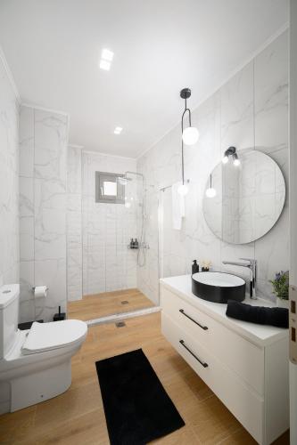 a white bathroom with a sink and a toilet at Zaros Springs Villa Avli in Zaros