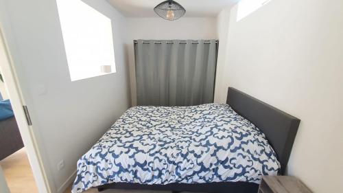 a bedroom with a bed with a blue and white comforter at Cozy and chic apartment 2 in Freyming