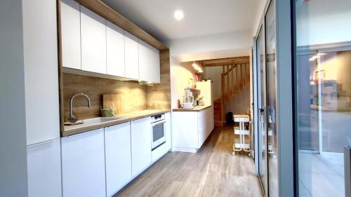 une cuisine avec des armoires blanches et un plancher en bois dans l'établissement VILLA des SABLES, à Saint-Georges-de-Didonne