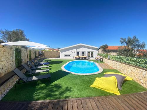 a backyard with a pool and chairs and an umbrella at Da Serra guesthouse in Porto de Mós