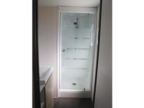 une salle de bain blanche avec une douche et un lavabo dans l'établissement BONNES VACANCES sur le Camping LA PRAIRIE, à Saint-Hilaire-de-Riez