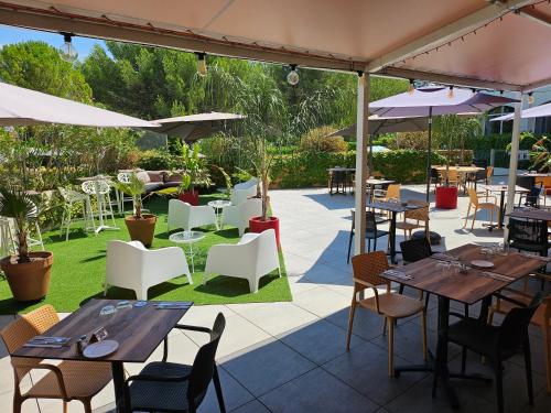 a restaurant with tables and chairs and umbrellas at Hôtel Birdy by Happyculture in Aix-en-Provence
