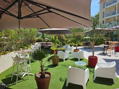 a patio with chairs and tables and an umbrella at Hôtel Birdy by Happyculture in Aix-en-Provence