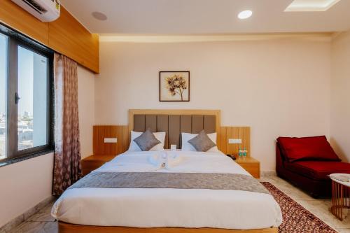 a bedroom with a large bed and a red couch at Daksh The Grand Goverdhan in Dwarka
