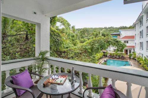 a balcony with a table and chairs and a pool at IVAAN Stays in Assagao