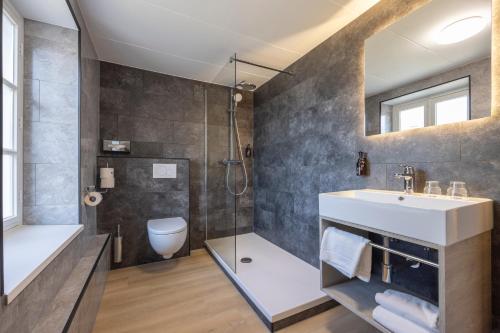 a bathroom with a shower and a sink and a toilet at Fletcher Hotel Restaurant De Burghoeve in Valkenburg