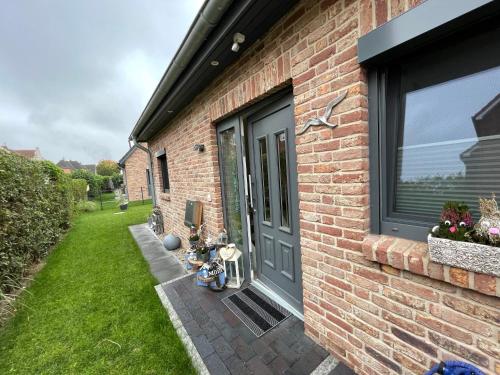 a brick house with a gray door and a yard at Ferienwohnungen Heimathafen und Hafenkante in Neustadt in Holstein