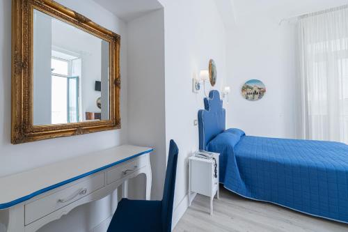 a bedroom with a blue bed and a mirror at Hotel Fontana in Amalfi