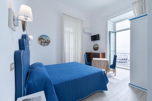 a blue bed in a white bedroom with a view of the ocean at Hotel Fontana in Amalfi