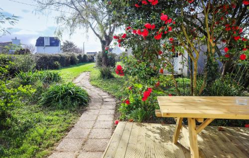 a wooden bench sitting next to a garden with red roses at 3 Bedroom Stunning Home In Plougasnou in Plougasnou