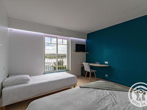 une chambre avec deux lits et un mur bleu dans l'établissement Villa rénovée à Cholet avec piscine privée et vue sur le lac, idéale pour 15 personnes - FR-1-622-105, à Cholet