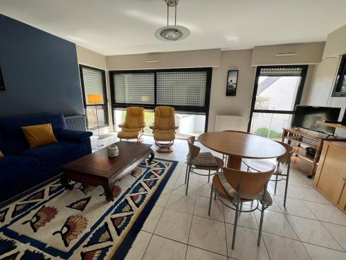 un salon avec un canapé bleu, une table et des chaises dans l'établissement Carnac joli appartement entre plage et ville!, à Carnac
