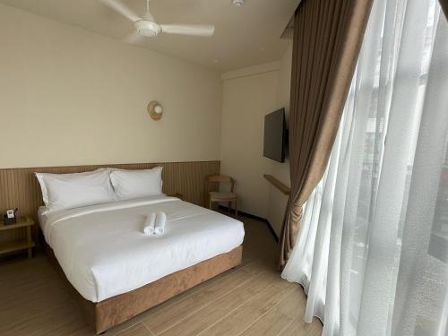 a bedroom with a white bed and a window at Hotel Mirda Puncak Alam in Bandar Puncak Alam