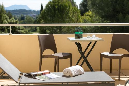 a chair and a table on a balcony with a view at Hôtel Birdy by Happyculture in Aix-en-Provence