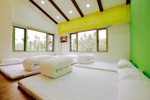 a room with four large beds in it with windows at Love B&B in Sanyi
