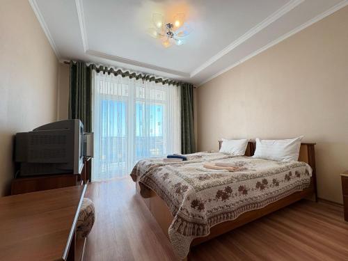 Tri Korony في شولبون آتا: غرفة نوم بها سرير وجهاز تلفزيون ونافذة