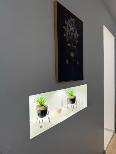 a white shelf with two plants on a wall at EXCEPTIONNEL Studio VERSAILLES in Le Chesnay