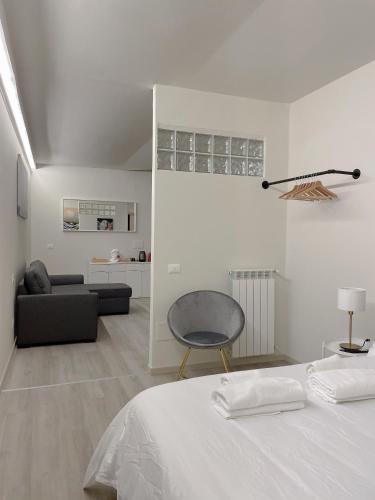 a white bedroom with a bed and a chair at 7Suites in Empoli