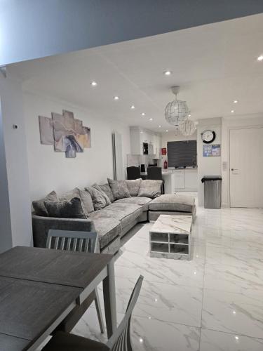 a living room with a large couch and a kitchen at A stylish 3 bedroom house or Apartment in Greenhithe - Available for booking as individual Room or as a Whole apartment - 11mins walk to Greenhithe Train Station, 7 mins drive to Bluewater shopping mall in Greenhithe