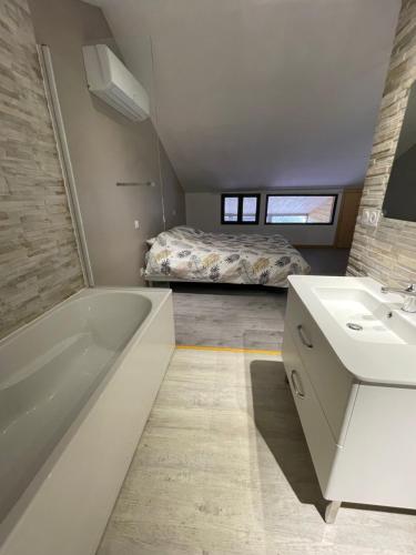 a bathroom with a tub and a sink and a bed at Maison Maxime Coeur de ville in Marciac