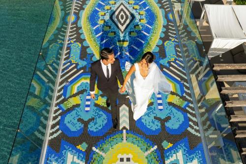 a bride and groom walking on a mosaic floor at W Punta de Mita in Punta Mita