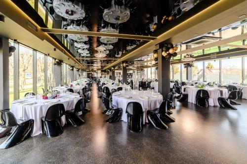 a banquet hall with white tables and black chairs at Golden Lion House Bed&Breakfast in Rumia