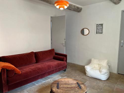 a living room with a red couch and a coffee table at Maison cosy en Provence Proche Golf Pont Royal in Alleins