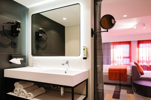 a bathroom with a white sink and a bedroom at Ostend Hotel in Ostend